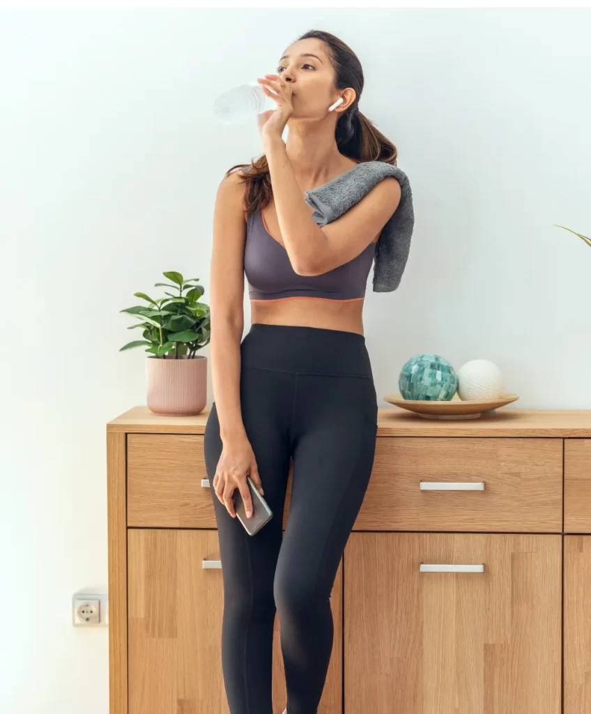 shot of sporty young woman drinking water while ta utc